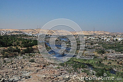 Abandoned huts and houses by the sea water with a sandy path from the mountains and a few trees Stock Photo