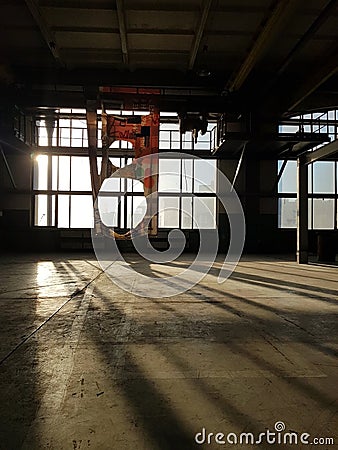 Abandoned industrial object with a torn banner on the wall. The sun is shining through the window. Beautiful shadows on the floor Stock Photo