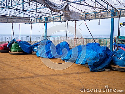 Abandoned Luna Park. Autodrom. Cars are covered with tarpaulins. Old carousels. Not working. Broken attraction. resort in winter. Stock Photo