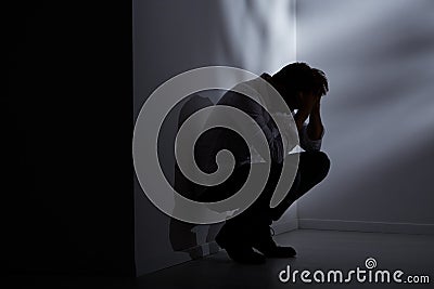 Abandoned man sitting beside wall Stock Photo