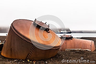 Abandoned norwegian whale hunter station rusty blubber tanks with cruise vessel in the bay , at Deception island, Antarctic Stock Photo