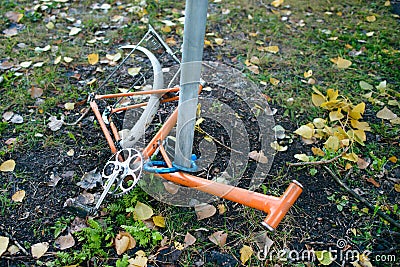 Abandoned old bicycle without wheels, chained to metal pole with blue locker. Stock Photo