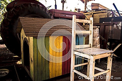 Abandoned pile of paraphernalia chairs, tractor, vibrant colored dog house and more at a shed Stock Photo