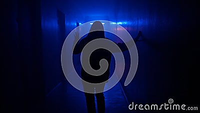 Portrait of female in hallway blue neon light. Close back shot woman walking cautiously in the dark corridor, holding up Stock Photo