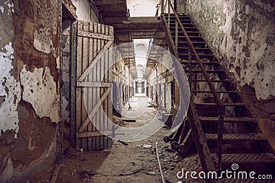 Abandoned prison cell walkway with old rusty stairs, doors and peeling walls. Stock Photo