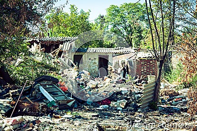 Abandoned ruin of house after grenade explosion in bombing with remains all over the yard Stock Photo