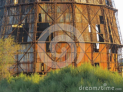 An abandoned, rusty industrial structure with multiple levels, exposed to elements The top is open, revealing interior Stock Photo