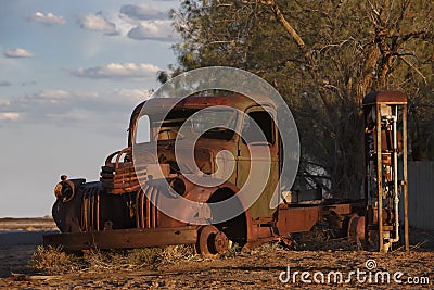 Abandoned rusty old pick up truck wreck sits derelict on the side of a road on sunset Stock Photo