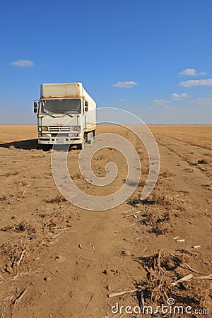 Abandoned rusty old truck on the empty desert highway road under the scorching sun Stock Photo