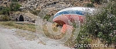 Abandoned sailboat on beach near ancient bridge Stock Photo