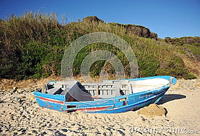 Abandoned small wooden boat -patera- on a beach near Tarifa, coast of Andalusia, Spain. Stock Photo