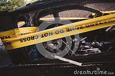 An abandoned, stolen burnt out blue car parked on the sideway parking spotÐ± tied with yellow do not cross stripe Editorial Stock Photo