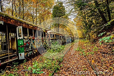 Abandoned Trolley Cars in Fall with rails in woods Stock Photo