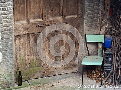 Abandoned village doorway with chair and wine bottle. Poignant. Stock Photo