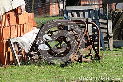 Abandoned vintage retro rusted agricultural farming equipment used to work with tractors on soil left in backyard surrounded with Stock Photo