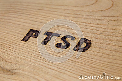 An abbreviation PTSD - post traumatic stress disorder - burned by hand on flat wooden board in diagonal composition Stock Photo
