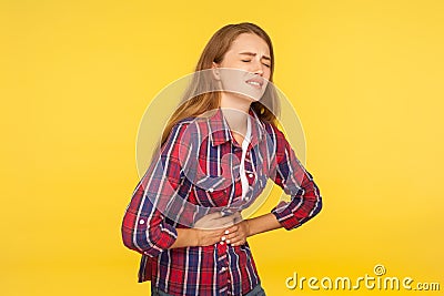 Abdominal pain. Portrait of unhealthy ginger girl in shirt clasping belly and suffering stomachache, indigestion symptoms Stock Photo
