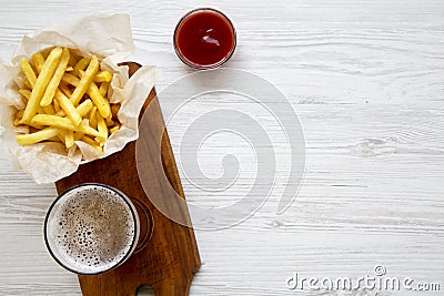From above french fries with ketchup and cold beer over white wooden background. Top view. Stock Photo