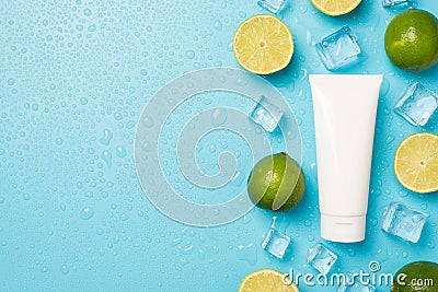 Above photo of pile of limes cubes of ice drops mint and tube of cream isolated on the blue background with blank space Stock Photo