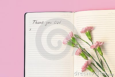 Above view of flowers on open paper notepad with handwritten words Thank you list. Gratitude journal Stock Photo