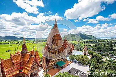 Above view of golden church with big buddha statue and rice field in Wat Tham Sua temple Stock Photo