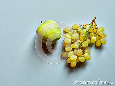 Isolated set of a green apple with a bunch of sweet seedless grapes in studio with blue background Stock Photo