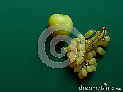 Isolated set of a green apples with a bunch of sweet seedless grapes in studio with green background Stock Photo