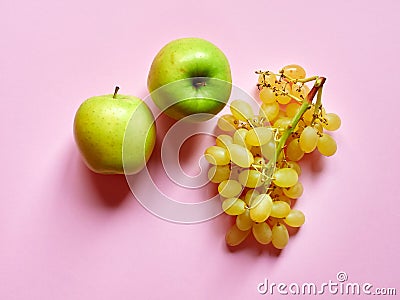 Isolated set of a green apples with a bunch of sweet seedless grapes in studio with millennial pink background Stock Photo