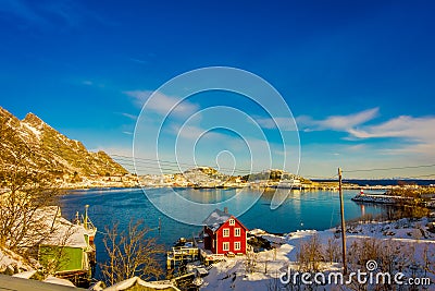 Above view of some wooden buildings in the bay with boats in the shore in Lofoten Islands surrounded with snowy Stock Photo