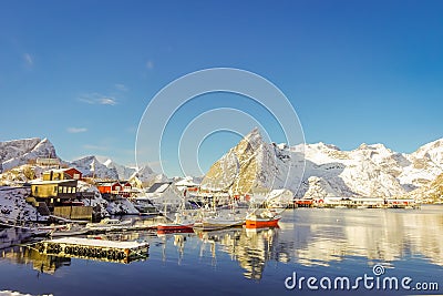 Above view of some wooden buildings in the bay with boats in the shore in Lofoten Islands surrounded with snowy Stock Photo