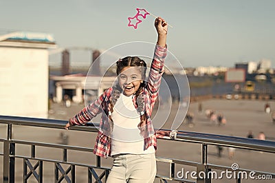 Absolutely thrilled. Happy party girl on urban background. Adorable girl holding prop glasses for party fun. Cute small Stock Photo