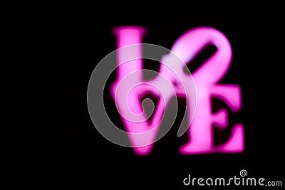 Abstact blurred Plastic pink sign of word LOVE on black background. Stock Photo