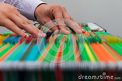 Abstract background colorful hanging file folders in drawer. Male hands looking document in a whole pile of full papers Stock Photo