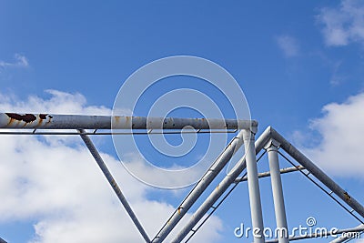 Abstract background of overhead pipes against a blue sky with clouds Stock Photo