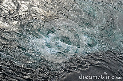 Abstract background. The waves of the sea water meet with underwater pointed rocks, forming whirlpools. Stock Photo