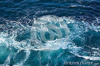 Abstract background. The waves of the sea water meet with underwater pointed rocks, forming whirlpools. Stock Photo