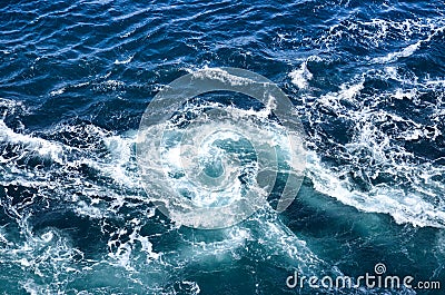 Abstract background. The waves of the sea water meet with underwater pointed rocks, forming whirlpools. Stock Photo