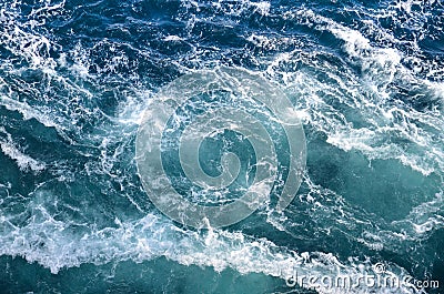 Abstract background. The waves of the sea water meet with underwater pointed rocks, forming whirlpools. Stock Photo