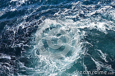 Abstract background. The waves of the sea water meet with underwater pointed rocks, forming whirlpools. Stock Photo