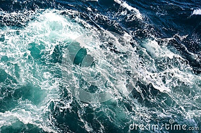 Abstract background. The waves of the sea water meet with underwater pointed rocks, forming whirlpools. Stock Photo