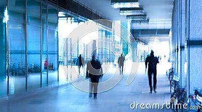 Abstract, blurred image of people walking via long tunnel with light at the background. Stock Photo