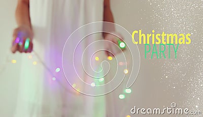 Abstract and bokeh image of young woman holding garland christmas lights and typography: CHRISTMAS PARTY. Holiday invitation conce Stock Photo