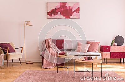 Abstract burgundy and pastel pink painting on empty white wall of fashionable living room interior with classy armchair and Stock Photo