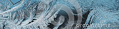 Abstract Christmas headline. Ice crystals on frozen window glass. Frost drawing closeup. Patterns of leaves and stems of magical Stock Photo