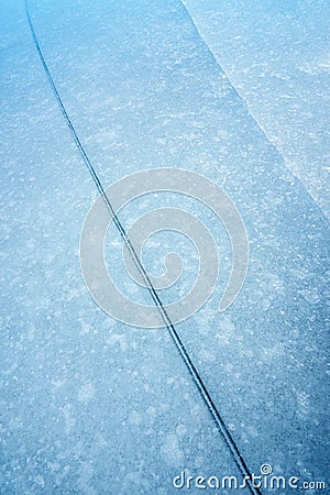 An abstract detailed vertical close up photograph of a crack or fault line in the blue frozen ice layer on a lake Stock Photo