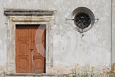 Stone wall with an old wooden door and a small window. Stock Photo