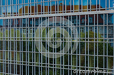 Abstract distorted reflection of historic house and green trees in mirrored glass wall of modern corporate building Stock Photo