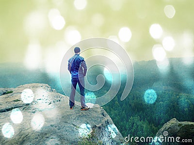 Abstract effect. Man stay on peak within daybreak and watch over misty landscape. Beautiful autumn Stock Photo