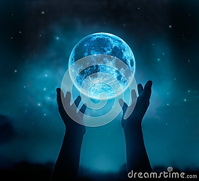 Abstract hands while praying at blue full moon with star in dark night sky background Stock Photo