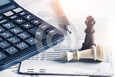 The abstract image of the both of black and white chess kings laying on the accounting document and a calculator, pen is placed ar Stock Photo